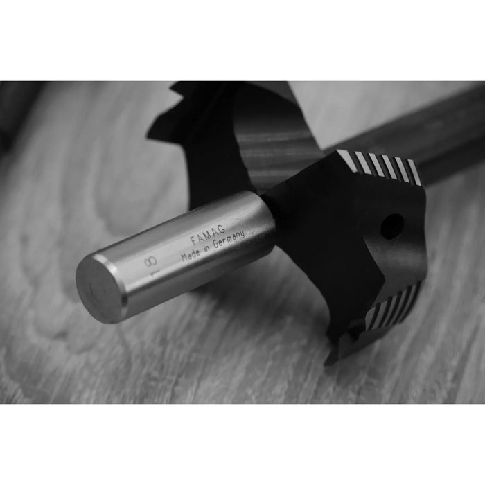 Close-up of a metal tool with 'FAMAG' branding on a wooden surface