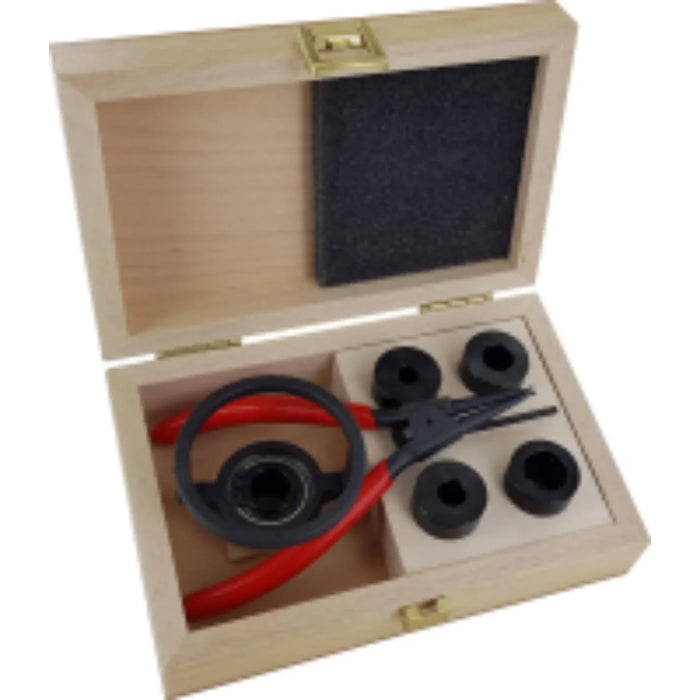 Wooden box with tools including a red and black pliers, and 5 black cylindrical depth stops on a white background.