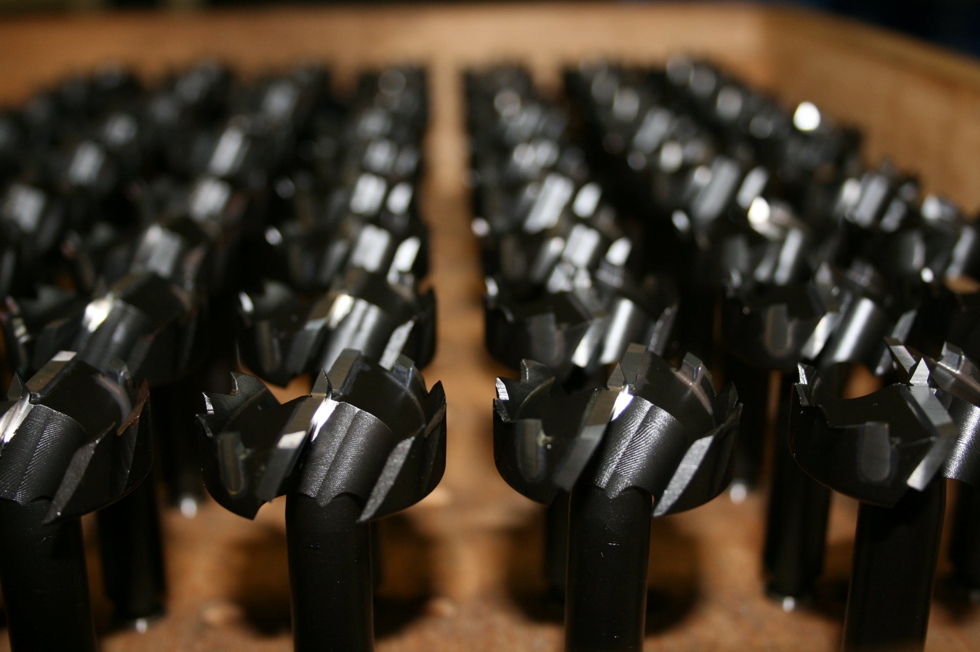 Close-up of black drill bits arranged on a wooden surface