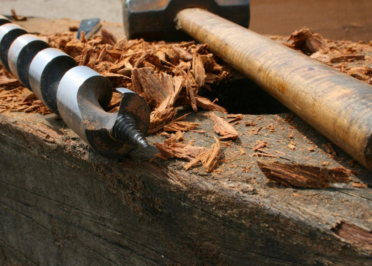 Metal Auger on a wooden surface with wood shavings
